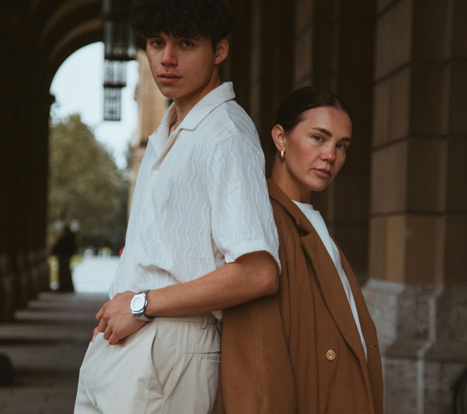 Sophisticated portrait of two adults posing in Munich's arched architecture.
