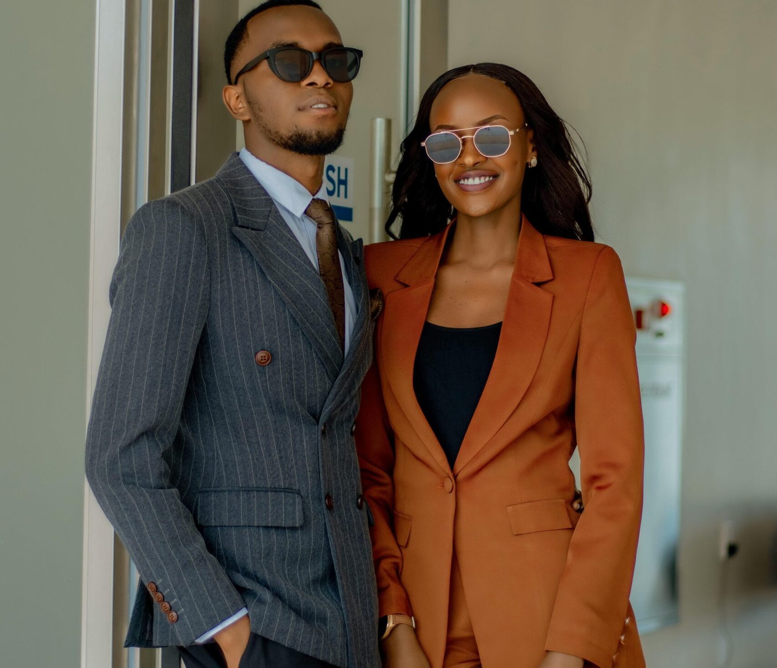 Confident African couple in stylish business suits indoors, showcasing modern fashion.